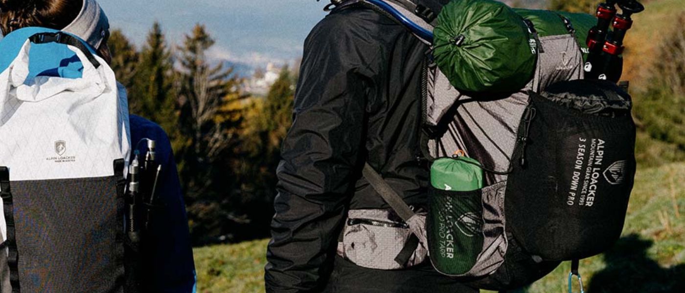 Eine Person trägt einen weiß-schwarzen Rucksack und eine Jacke, passend für Outdoor-Aktivitäten wie Wandern.