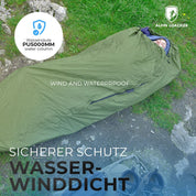 Bivi PRO - leichter Biwaksack, grün, auf Gras und Felsen, mit Kopf im isolierten Kapuze, nahe Wanderschuhe; wasser- und winddicht, 5000mm Wassersäule, Alpin Loacker Logo.