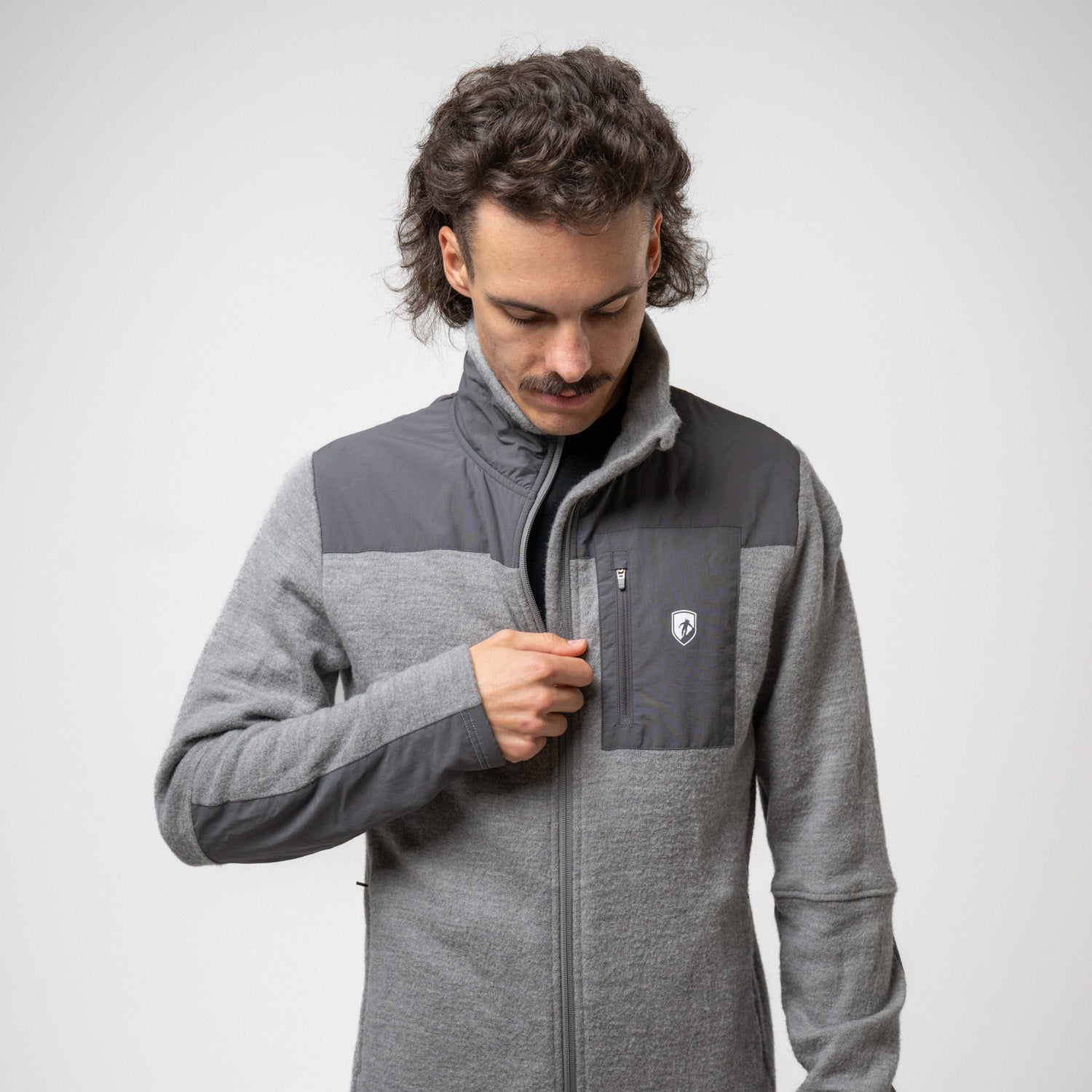 Model trägt grauen Merino Fleece aus 100% Merinowolle, mit moderner Doppel-Fleece Struktur und Zip tasche im Brustbereich