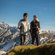 Wanderpärchen steht in grauen und grünen Merino Fleece Jacken auf dem Berg. Man erkennt die praktische Zip Brusttasche.