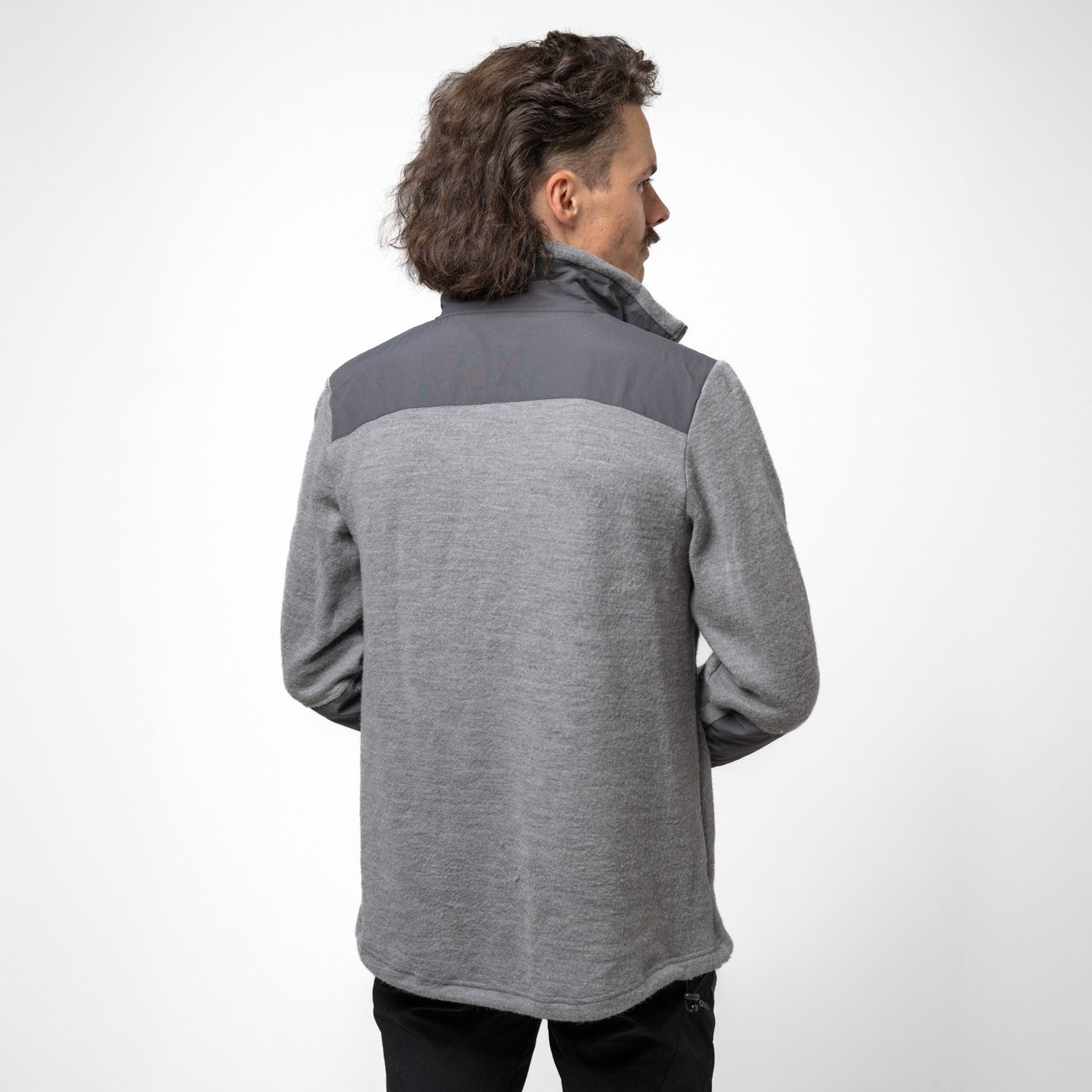 Model trägt grauen Merino Fleece aus 100% Merinowolle, mit moderner Doppel-Fleece Struktur und robusten Schulterpartien