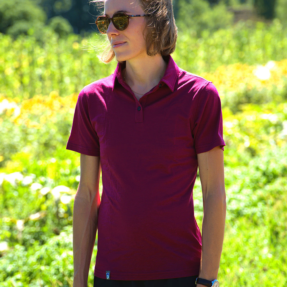 Person trägt Merino Poloshirt Damen von Alpin Loacker in einer sonnigen Wiese, ideal für Outdoor-Aktivitäten durch seine atmungsaktive und temperaturregulierende Merinowolle.