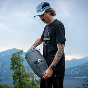Mann am See mit Alpin Loacker Drybag Ultraleicht, hält ultraleichten, wasserdichten Packsack, ideal für Outdoor-Aktivitäten, vor Bergkulisse.