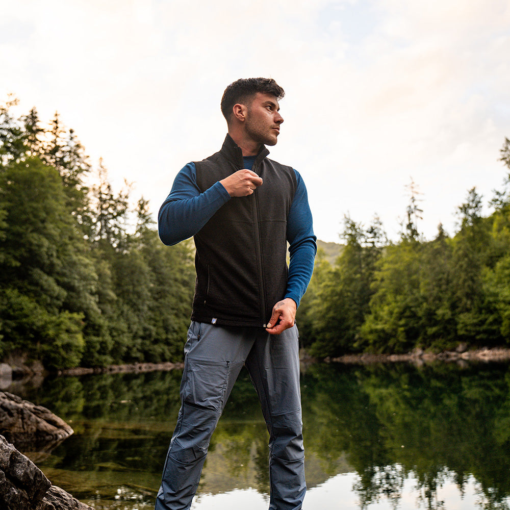 Mann am See mit Merino Weste Herren 270 g/m2, zippend. Ideal als Midlayer für Outdoor-Aktivitäten, bietet Temperaturregulierung und Komfort.