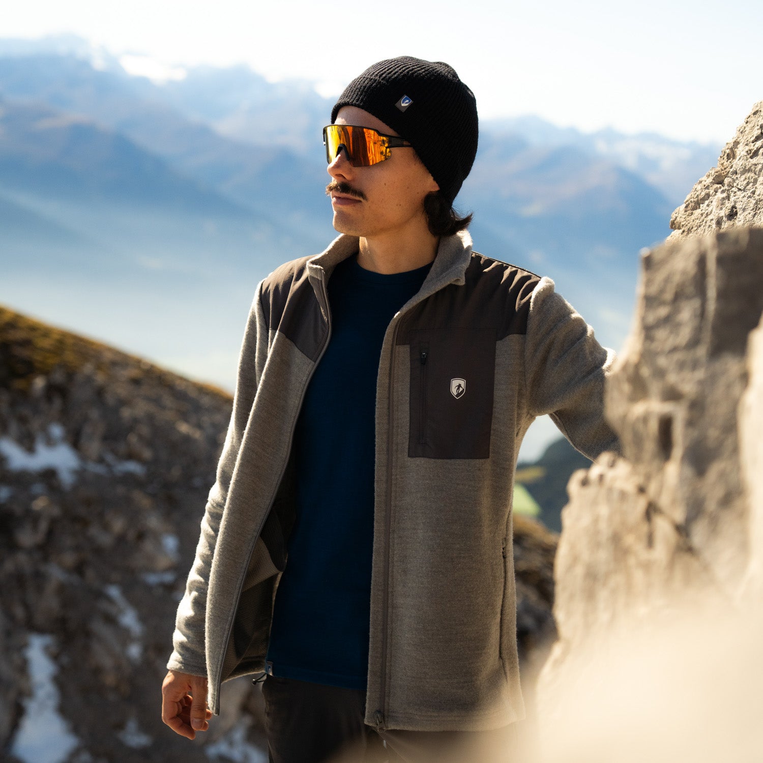 Model trägt grauen Merino Fleece aus 100% Merinowolle am Berg, der perfekte Midlayer für kühlere Tage