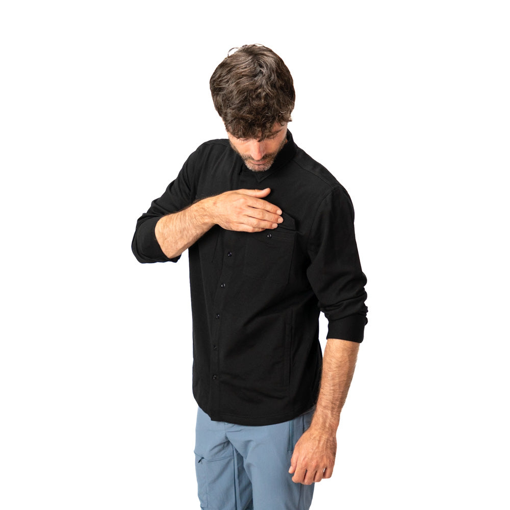 Mann trägt schwarzes Merino Wanderhemd und öffnet Brusttasche