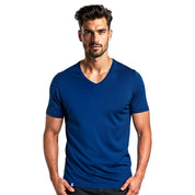 Merino V-Neck T-Shirt Herren, kurzärmelig, ideal für Outdoor-Enthusiasten, getragen von jungem Mann, stehend, Hände an den Hüften, schlichtes Design.