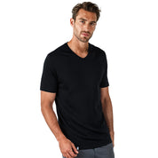 Männliches Model trägt Merino V-Neck T-Shirt Herren, perfekt für Outdoor-Aktivitäten, kombiniert mit schlichten Hosen, vor weißem Hintergrund. Ideal für modebewusste Outdoor-Enthusiasten.