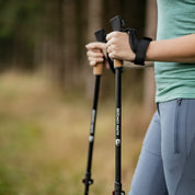 Person hält Teleskop Nordic Walking Stöcke aus Aluminium mit Korkgriffen von Alpin Loacker auf einem Waldweg.