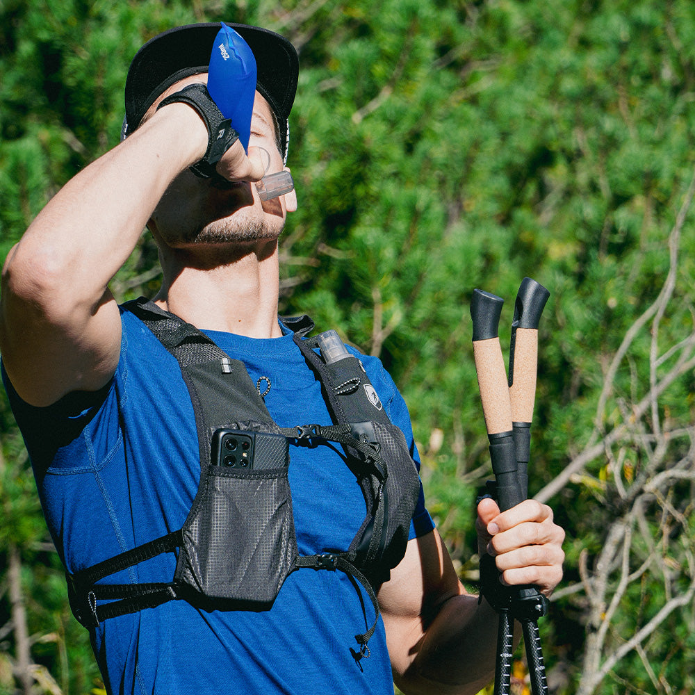 Athlet nutzt Faltbare Trailrunning Stöcke aus Carbon mit ergonomischen Korkgriffen und Smartphone-tauglichem Laufwestenfach, ideal für Trailrunner und Wanderer.