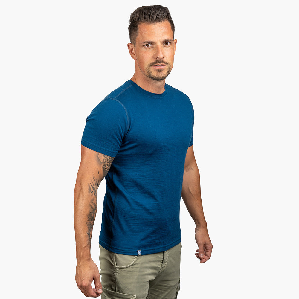 Mann trägt Alpin Loacker 100% Merino T-Shirt Herren 180 g/m², ideal für Outdoor-Aktivitäten, aus atmungsaktiver, geruchsneutraler Merinowolle, vor neutralem Hintergrund.