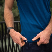 Merino Coolmax T-Shirt Herren 150 g/m2, präsentiert einen Mann, der das Logo am Saum zeigt. Ideal für Outdoor-Aktivitäten, kombiniert Merinowolle mit Coolmax® für Komfort und Funktion.