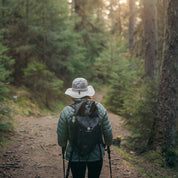Hiker mit Leichter Rucksack wasserdicht, Trekkingstöcken im Wald. Perfekt für Outdoor-Abenteuer, bietet robusten, wasserdichten Schutz und vielseitige Befestigungsmöglichkeiten.