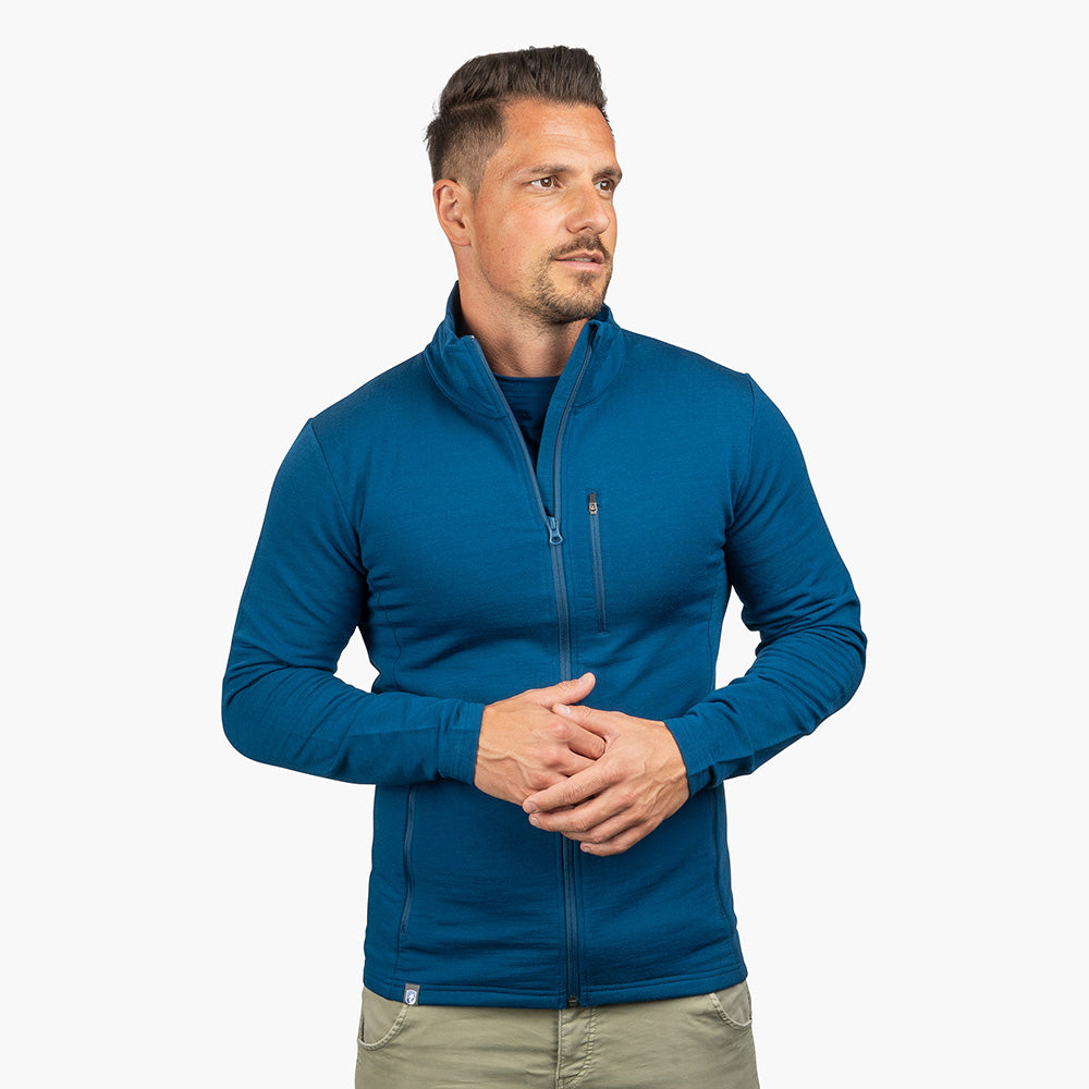 Mann trägt Merino Jacke Herren 270 g/m², sportlich geschnitten, ideal für Outdoor-Abenteuer. Hochwertige Merinowolle sorgt für Komfort und Vielseitigkeit.
