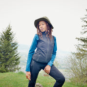Frau auf Hügel trägt Merino Weste Damen 270g/m2 von Alpin Loacker, ideal für Outdoor-Aktivitäten. Figurbetont, vielseitig, aus Merinowolle mit Bambusviskose, sportlicher Schnitt.