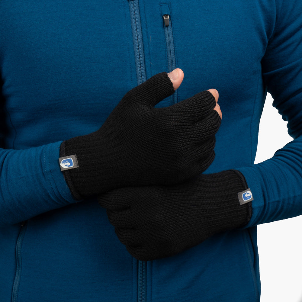 Person mit blauem Oberteil trägt fingerlose Merino Handschuhe Damen & Herren von Alpin Loacker, ideal für Outdoor-Abenteuer. Hände vor dem Körper verschränkt.