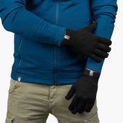 Person mit blauen Jacke trägt schwarze Merino Handschuhe Damen & Herren, Classic und fingerlos, von Alpin Loacker, zeigt sie gekreuzt für Outdoor-Aktivitäten.