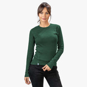 Junge Frau trägt das Merino Langarmshirt Damen 150 g/m2 von Alpin Loacker, ideal für Outdoor-Aktivitäten, aus temperaturregulierender Merinowolle, casual Pose, weiße Kulisse.