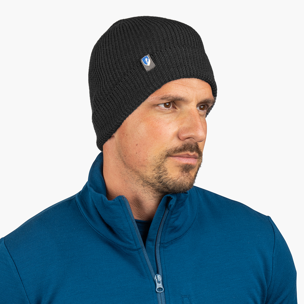 Mann trägt Merino Mütze Herren & Damen Strick 230g/m² in Schwarz, mit Logo. Perfekt für Outdoor-Aktivitäten dank temperaturregulierender Merinowolle.