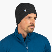 Mann trägt Merino Mütze Herren & Damen Strick 230g/m² in Schwarz, mit Logo. Perfekt für Outdoor-Aktivitäten dank temperaturregulierender Merinowolle.