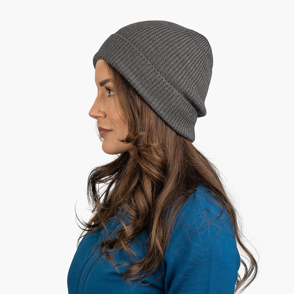 Seitenprofil einer jungen Frau, die eine Merino Mütze Herren & Damen Strick 230g/m² in mittelgrau trägt. Ideal für Outdoor-Aktivitäten.