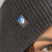Person trägt eine Merino Mütze Herren & Damen Strick 230g/m2 mit Schild-Logo, ideal für Outdoor-Aktivitäten dank weicher, temperaturregulierender Merinowolle.