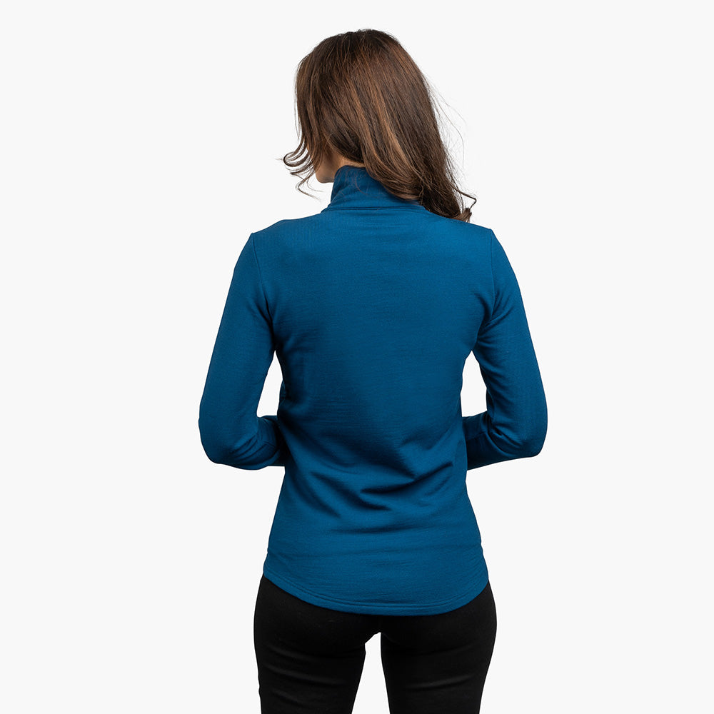 Rückansicht einer Frau in der Merino Jacke Damen 270 g/m2, tealblauer Rollkragen, sportlicher Schnitt, ideal für Outdoor-Abenteuer und Alltag.