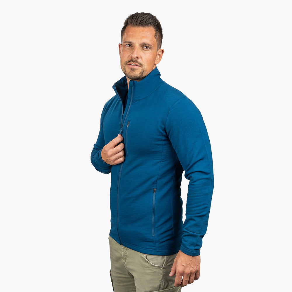 Modell trägt die Merino Jacke Herren 270 g/m² mit Reißverschluss, kombiniert mit olivgrünen Cargo-Hosen, ideal für Outdoor-Aktivitäten und Alltag.