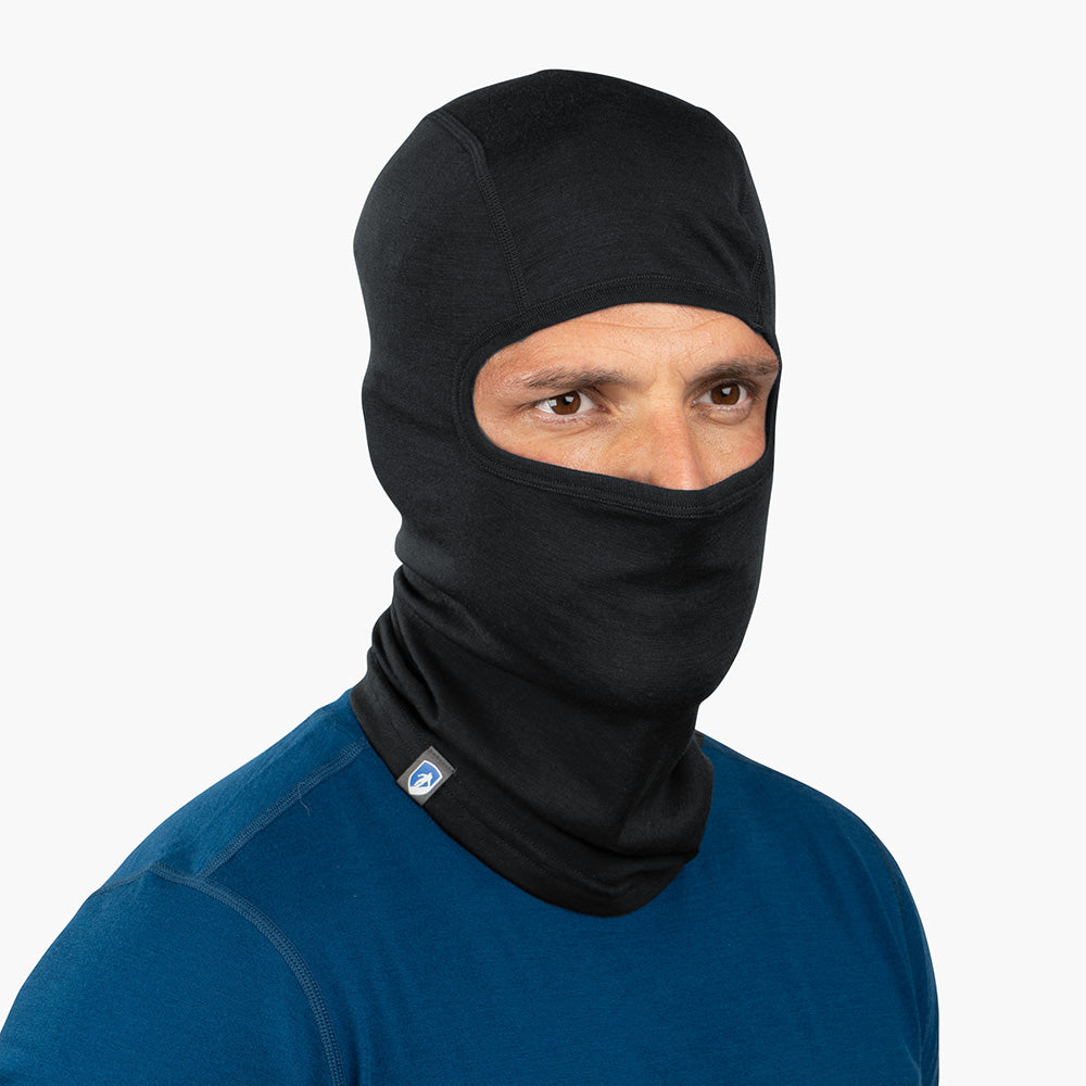 Person trägt Merino Sturmhaube und Skimaske Herren & Damen, die Gesicht und Kopf bedeckt, mit Augen- und Nasenöffnung, ideal für Outdoor-Aktivitäten bei kaltem Wetter.
