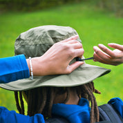 Person im Freien mit Sonnenhut mit UV Schutz Unisex, passt Kinnband an. Der Hut bietet UV-Schutz und ist ideal für Outdoor-Aktivitäten.