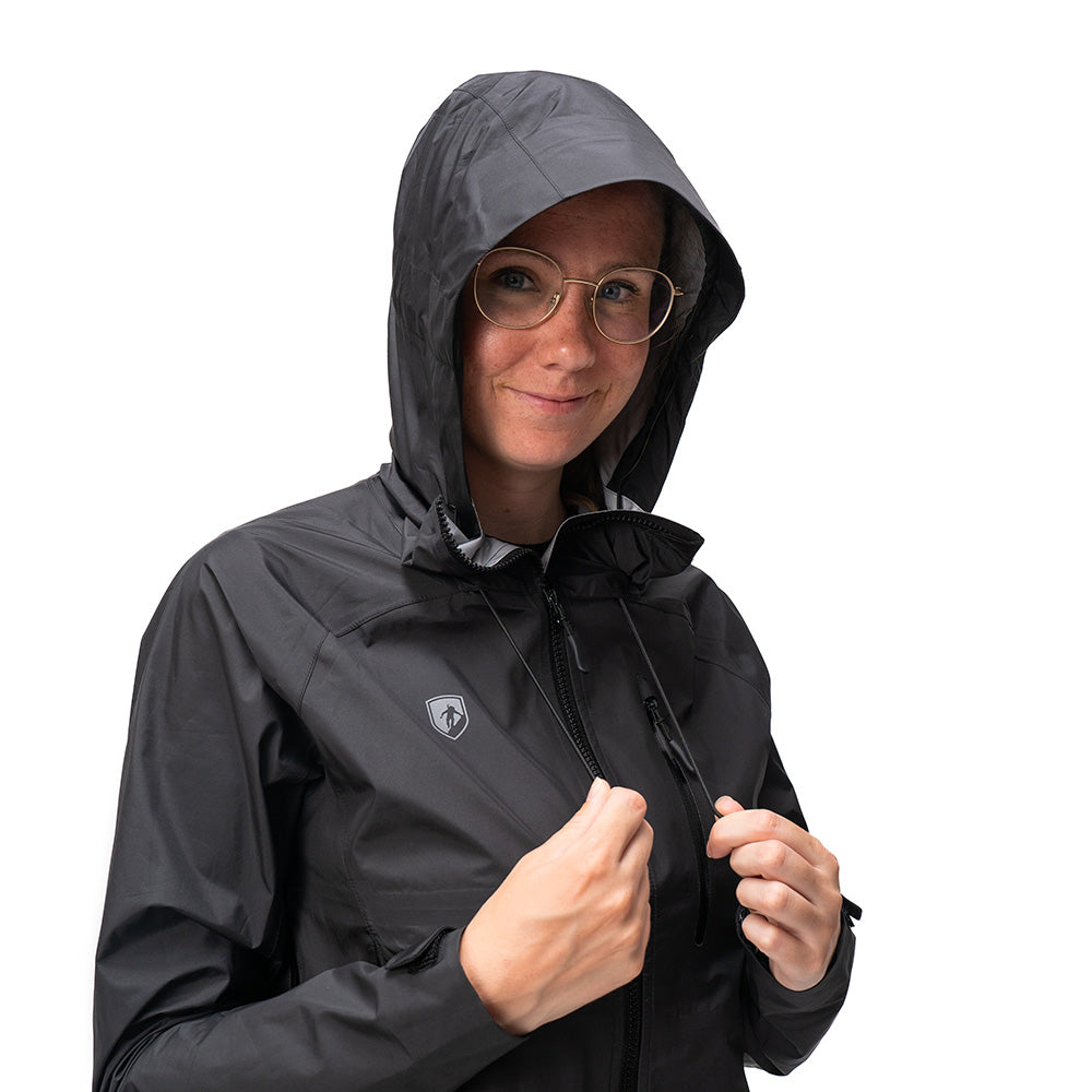 Person trägt schwarze 3 Lagen Damen Hardshell Regenjacke mit Kapuze und Logo, hält den Reißverschluss. Ideal für vielseitige Outdoor-Aktivitäten, wasser- und winddicht.