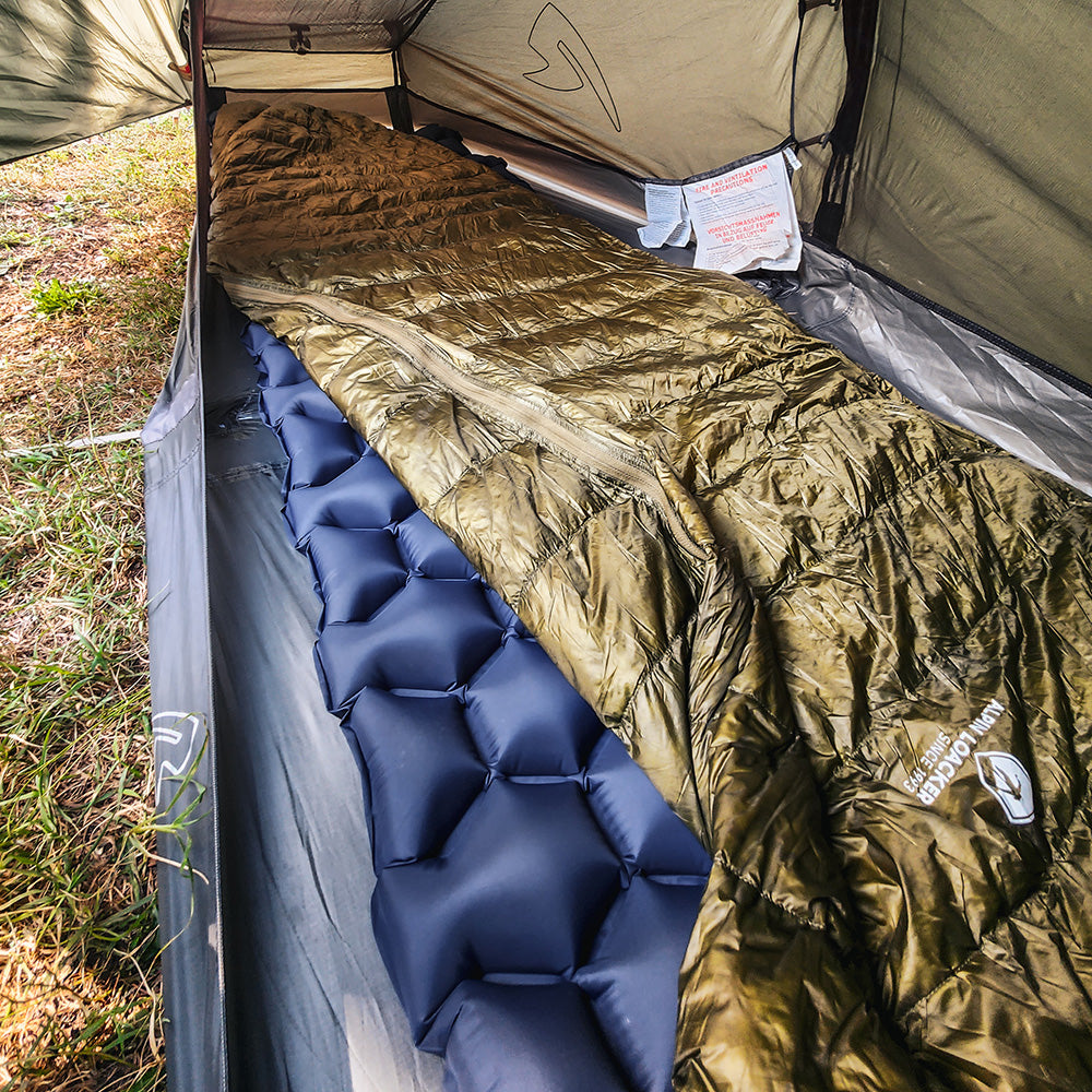 Innenansicht eines Zeltes mit einem blauen Schlafpad und dem Ultra leichter Daunen Sommerschlafsack 290g in Olivgrün, ideal für Outdoor-Abenteuer.