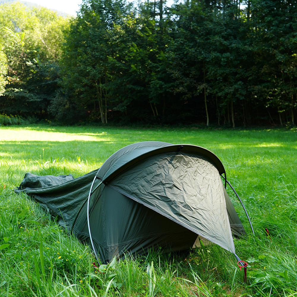 Ultraleichtes Bivy Zelt 965g auf einer Wiese, aufgestellt mit gebogenen Stangen und Heringen, ideal für wetterfeste, solo Abenteuer in der Natur.