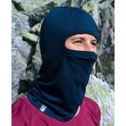 Person trägt Merino Sturmhaube und Skimaske Herren & Damen in felsiger Outdoor-Umgebung, zeigt nur Augen und Nase, ideal für kalte Outdoor-Aktivitäten.