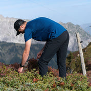 Mann inspiziert Pflanzen in den Bergen, trägt das 100% Merino T-Shirt Herren 180 g/m2 von Alpin Loacker, ideal für Outdoor-Aktivitäten.