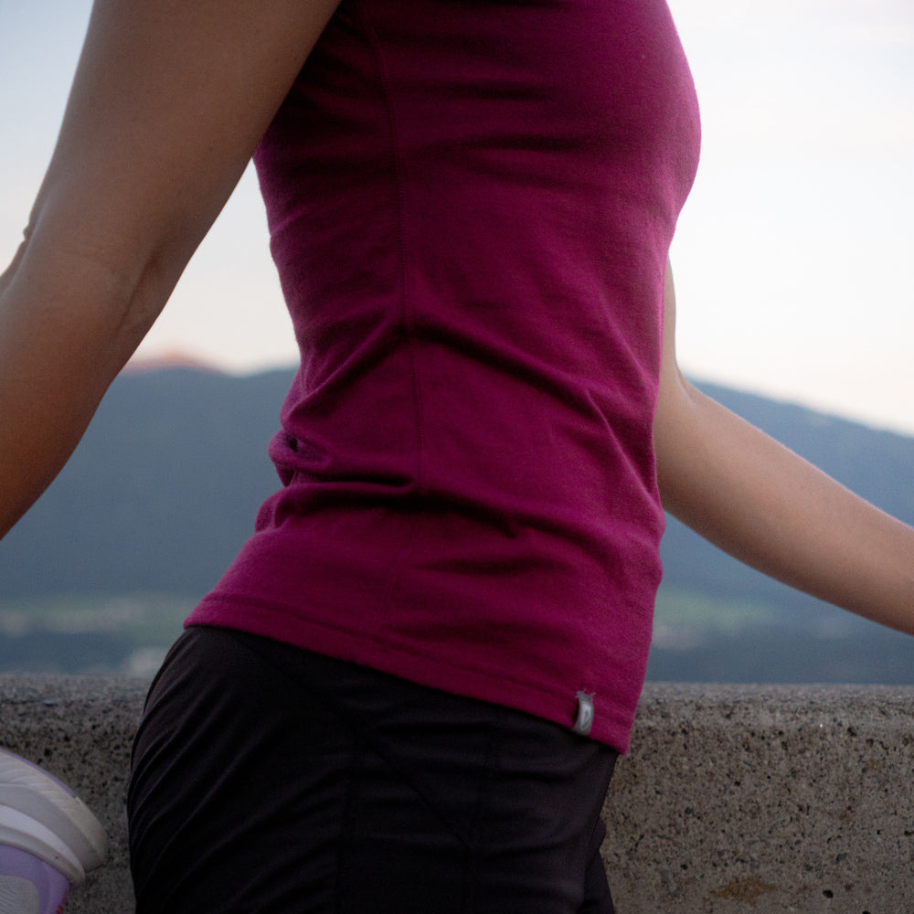 Person trägt ein Merino Coolmax T-Shirt Damen 150 g/m2, lehnt an einer Wand. Ideal für Outdoor-Aktivitäten, bietet es Komfort und Temperaturausgleich durch Merinowolle und Coolmax-Technologie.