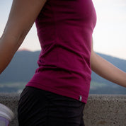 Person trägt ein Merino Coolmax T-Shirt Damen 150 g/m2, lehnt an einer Wand. Ideal für Outdoor-Aktivitäten, bietet es Komfort und Temperaturausgleich durch Merinowolle und Coolmax-Technologie.