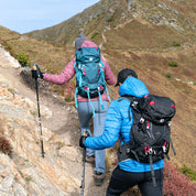 Zwei Wanderer auf felsigem Bergpfad mit dem 35 Liter Wanderrucksack Herren & Damen von Alpin Loacker, ideal für Outdoor-Abenteuer, ausgestattet mit Trekkingstöcken.
