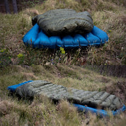 UL Down Quilt 450g auf blauem Luftmatratze auf Gras; ideal für ultraleichtes Camping mit hoher Wärmeisolierung und minimalem Gewicht.