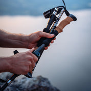 Nahaufnahme von Händen, die faltbare Wanderstöcke aus Carbon mit ergonomischem Korkgriff und leichtem Design zusammenbauen, ideal für anspruchsvolle Outdoor-Aktivitäten.
