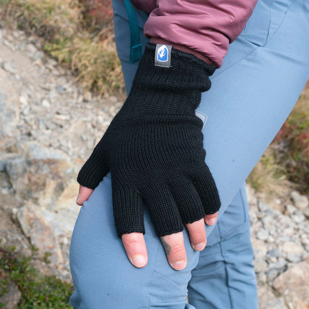 Nahaufnahme einer Person, die Merino Handschuhe Damen & Herren, fingerlos, trägt und auf einem felsigen Outdoor-Pfad steht, ideal für vielseitige Outdoor-Abenteuer.