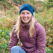 Junge Frau in lila-mauver Jacke trägt Merino Halstuch Herren & Damen, ideal für Outdoor-Aktivitäten. Atmungsaktiv und temperaturregulierend, perfekt für kühle Bedingungen.