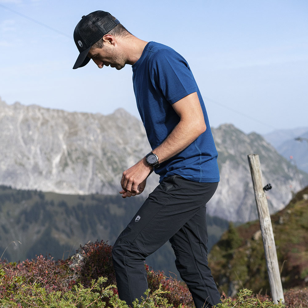 Mann in 100% Merino T-Shirt Herren 180 g/m2 wandert über steinigen Hang, ideal für Outdoor-Aktivitäten, symbolisiert Komfort und Funktionalität von alpinloacker.com.