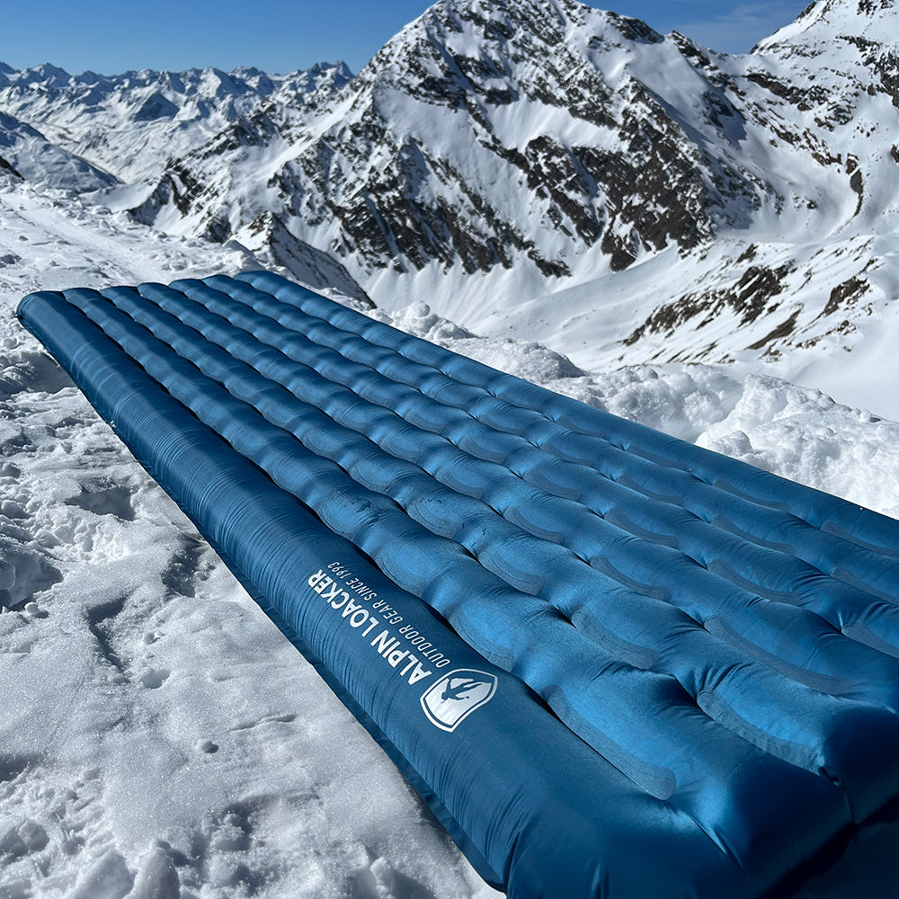 Leichte Isomatte für 4 Jahreszeiten von Alpin Loacker auf verschneitem Hang, ideal für Trekking und Wintercamping mit exzellenter Isolierung und Komfort.