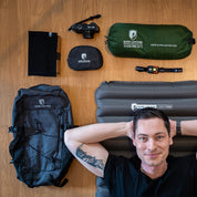 Mann auf Light Pro Isomatte, umgeben von Alpin Loacker Campingausrüstung, darunter der leichte 30L Allround Rucksack für Wandern & Reisen mit Dyneema Ripstop-Nylon.