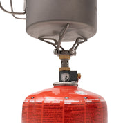 Ultraleichter Gaskocher aus Titan 45g, montiert auf roter Gaskartusche, mit Topf auf stabilen Stützen. Ideal für Outdoor-Abenteuer und minimalistische Camping-Touren.