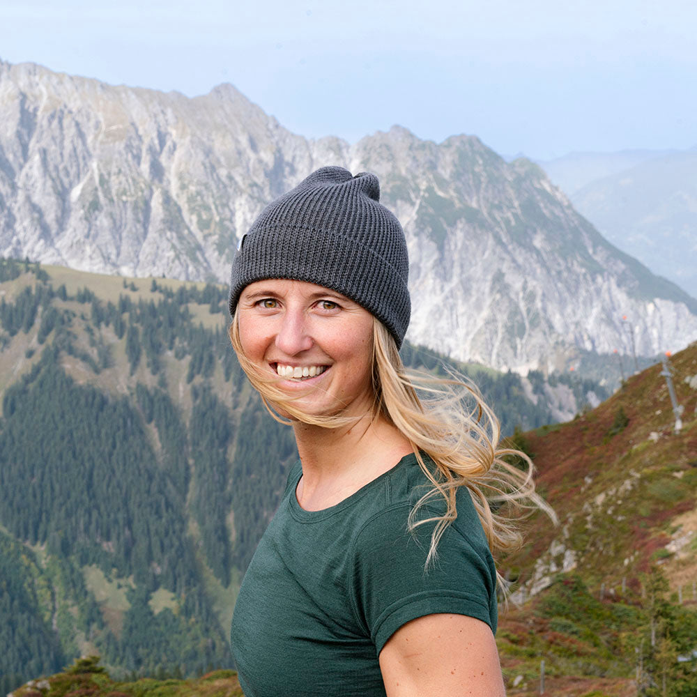 Junge Frau trägt 100% Merino T-Shirt Damen 180g/m2 in bergiger Umgebung, ideal für Outdoor-Aktivitäten, aus nachhaltiger Merinowolle, komfortabel und funktional.