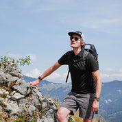 Mann steigt felsigen Hang hinauf, trägt Merino Polo Shirt Herren, ideal für Outdoor-Aktivitäten; atmungsaktiv, temperaturregulierend, geruchsresistent, nachhaltig.