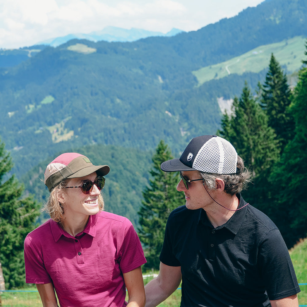 Zwei Personen in Merino Poloshirt Damen genießen die Berglandschaft; ideal für Outdoor-Aktivitäten dank atmungsaktiver, temperaturregulierender Merinowolle.