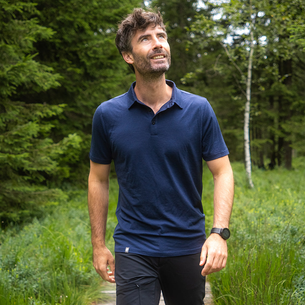 Mann in Merino Polo Shirt Herren auf Waldpfad, genießt Natur. Ideal für Outdoor-Aktivitäten dank atmungsaktiver und temperaturregulierender Merinowolle von alpinloacker.com.